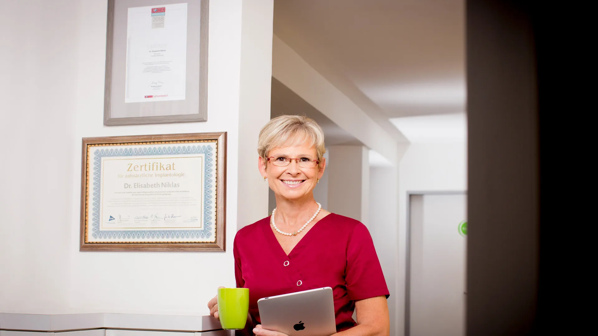 Zahnärztin Dr. Niklas: Die Zahnärztin steht vor ihrer Urkunde vom Zertifikat.