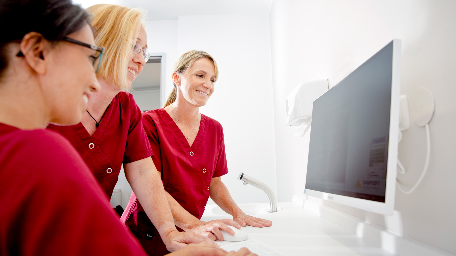 Spaß am Behandeln: Zahnmedizinische Fachangestellte schauen auf die digitale Patientenakte.